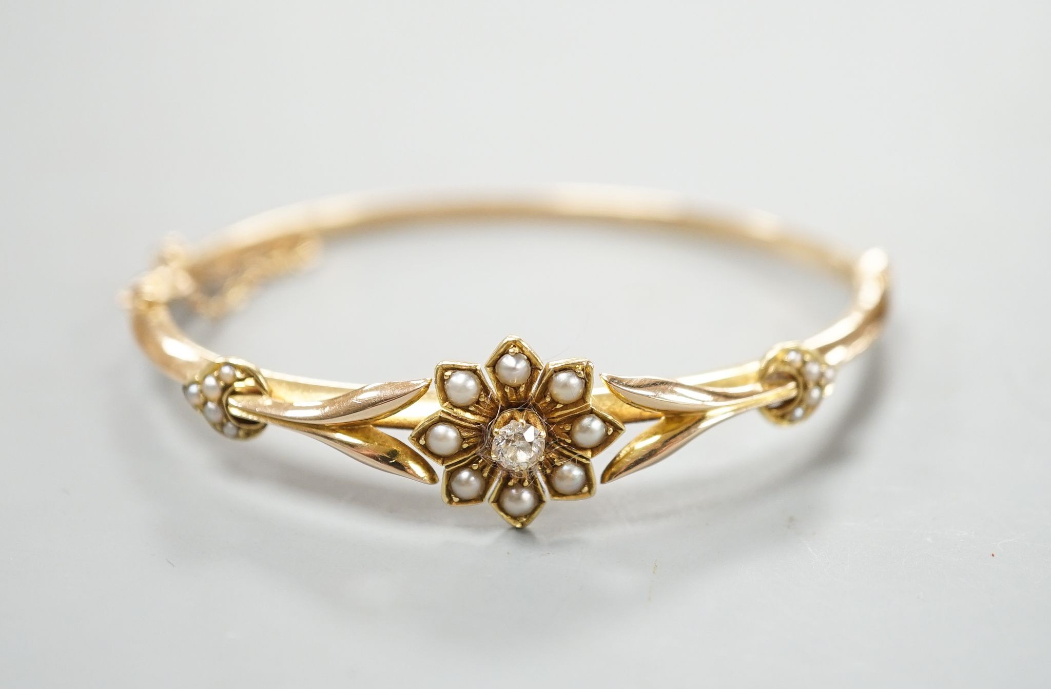 An early 20th century yellow meta diamond and seed pearl set hinged bangle, gross 9.5 grams.